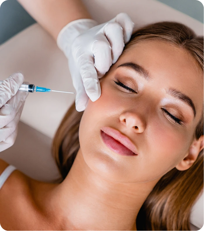 Clinician injecting cheek filler into a patient's cheekbone during a cosmetic procedure